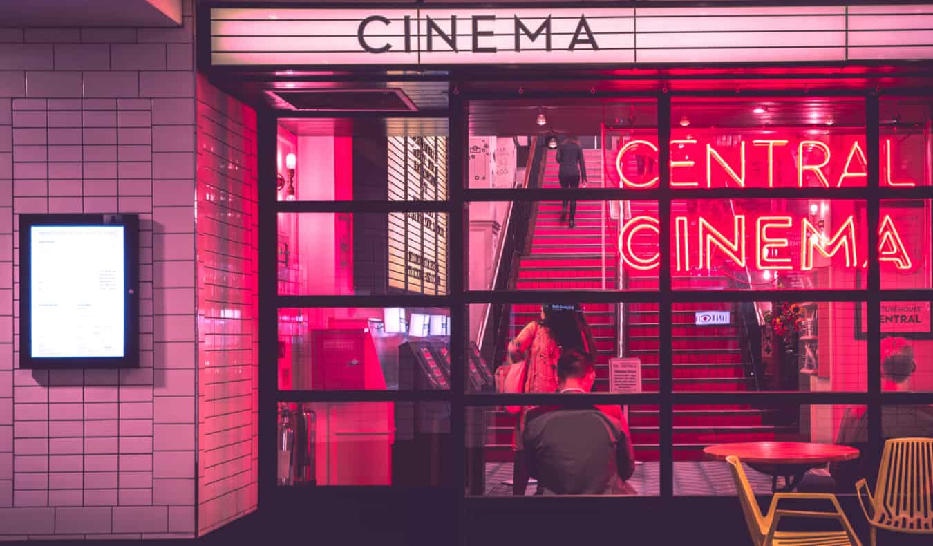 Cinema noturno iluminado com luz neon rosa.