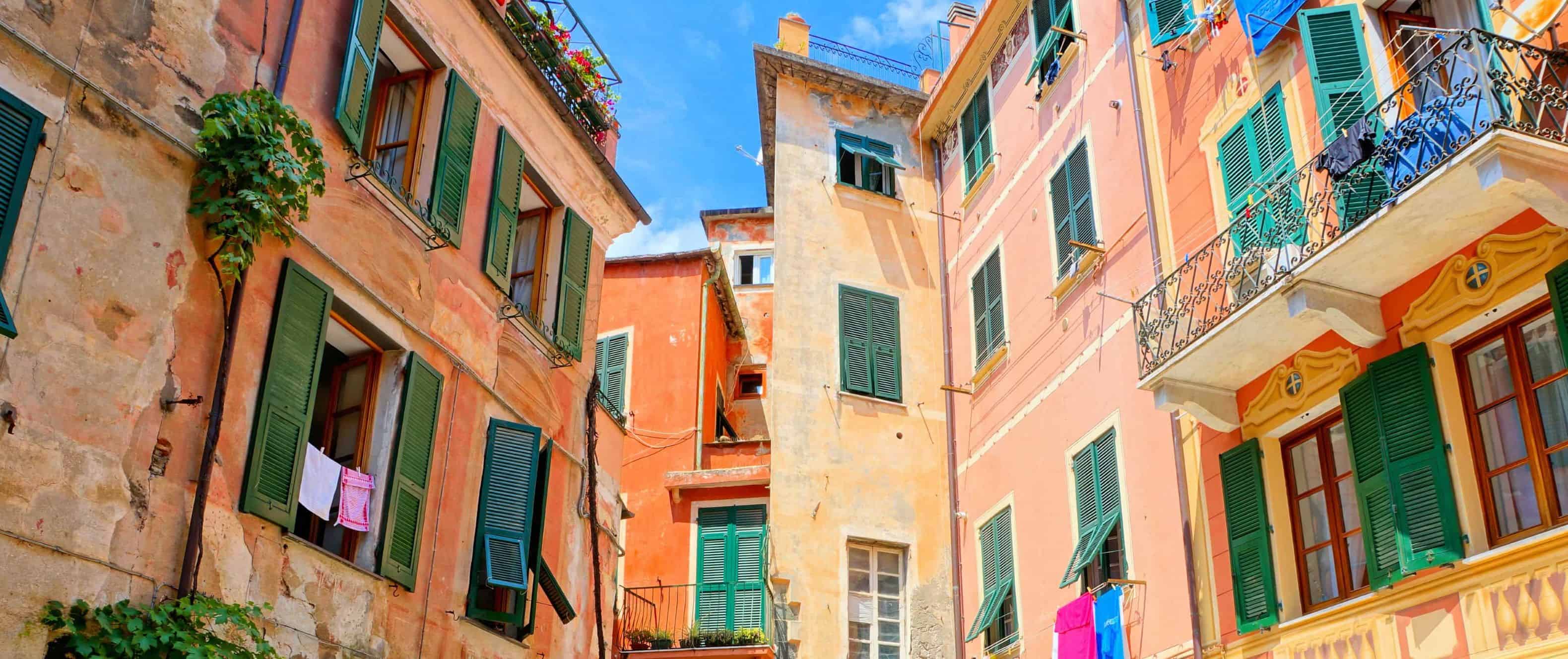 Edifícios laranja multicoloridos e uma pequena área com um restaurante em chinkve-terre, Itália.