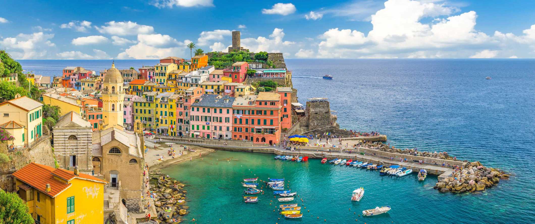 Edifícios coloridos e um porto cheio de barcos na cidade de Vernazza, na região de Chinkwe-Terre, Itália.