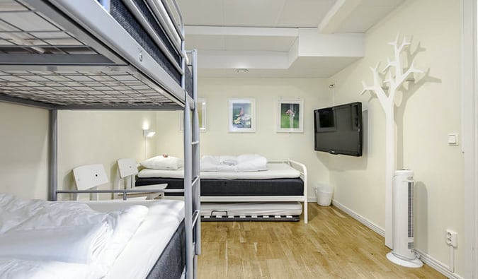 Uma sala branca e minimamente decorada com beliches e uma cama de casal no albergue da cidade, Estocolmo