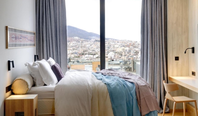Um hóspede simples, mas aconchegante, no hotel Coco-Mat com janelas do chão ao teto com vista para a cidade de Atenas, Grécia