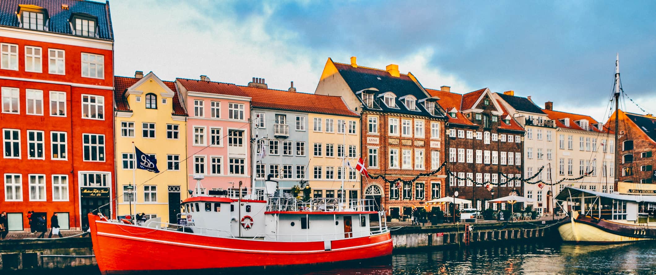 Ainda mais edifícios mult i-coloridos ao longo do canal com barcos em Copenhague, Dinamarca