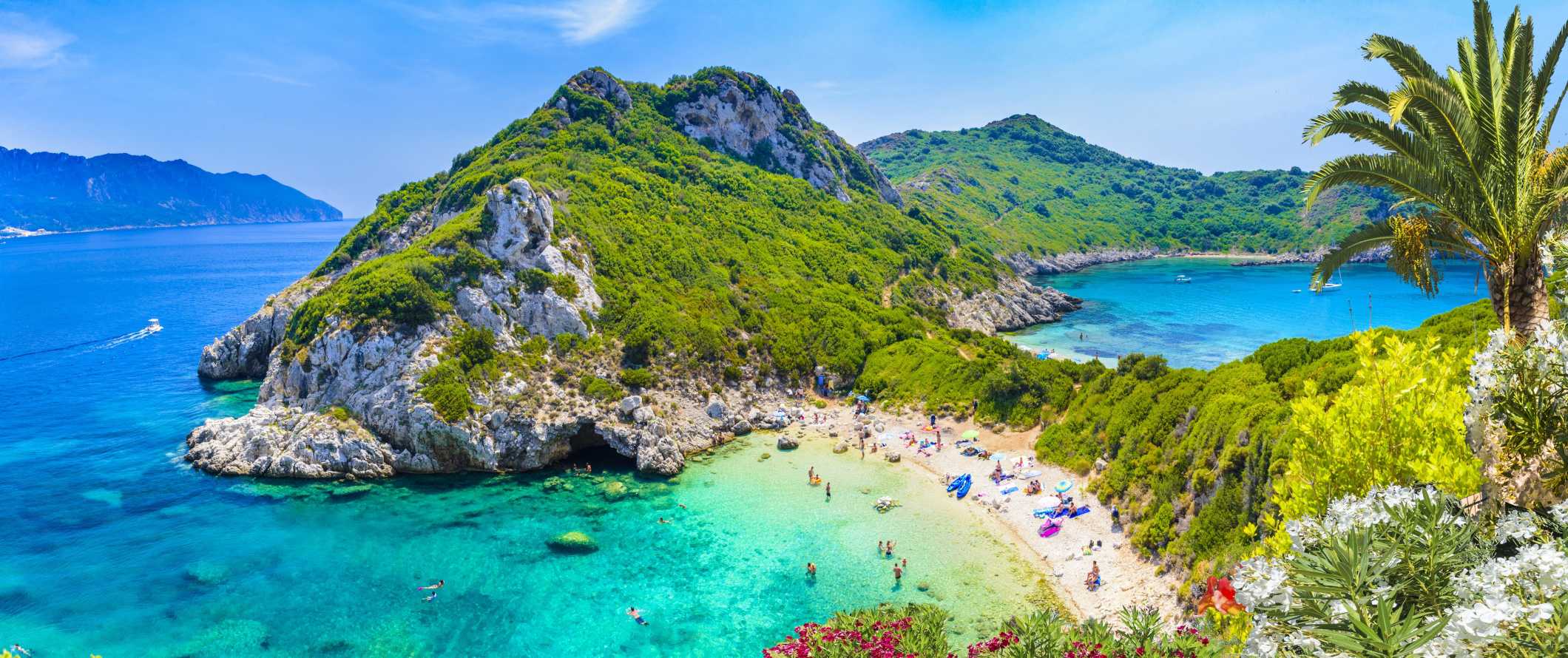 As pessoas descansam e tomam banho na praia com colinas exuberantes ao fundo e água turquesa transparente em Corfu, Grécia