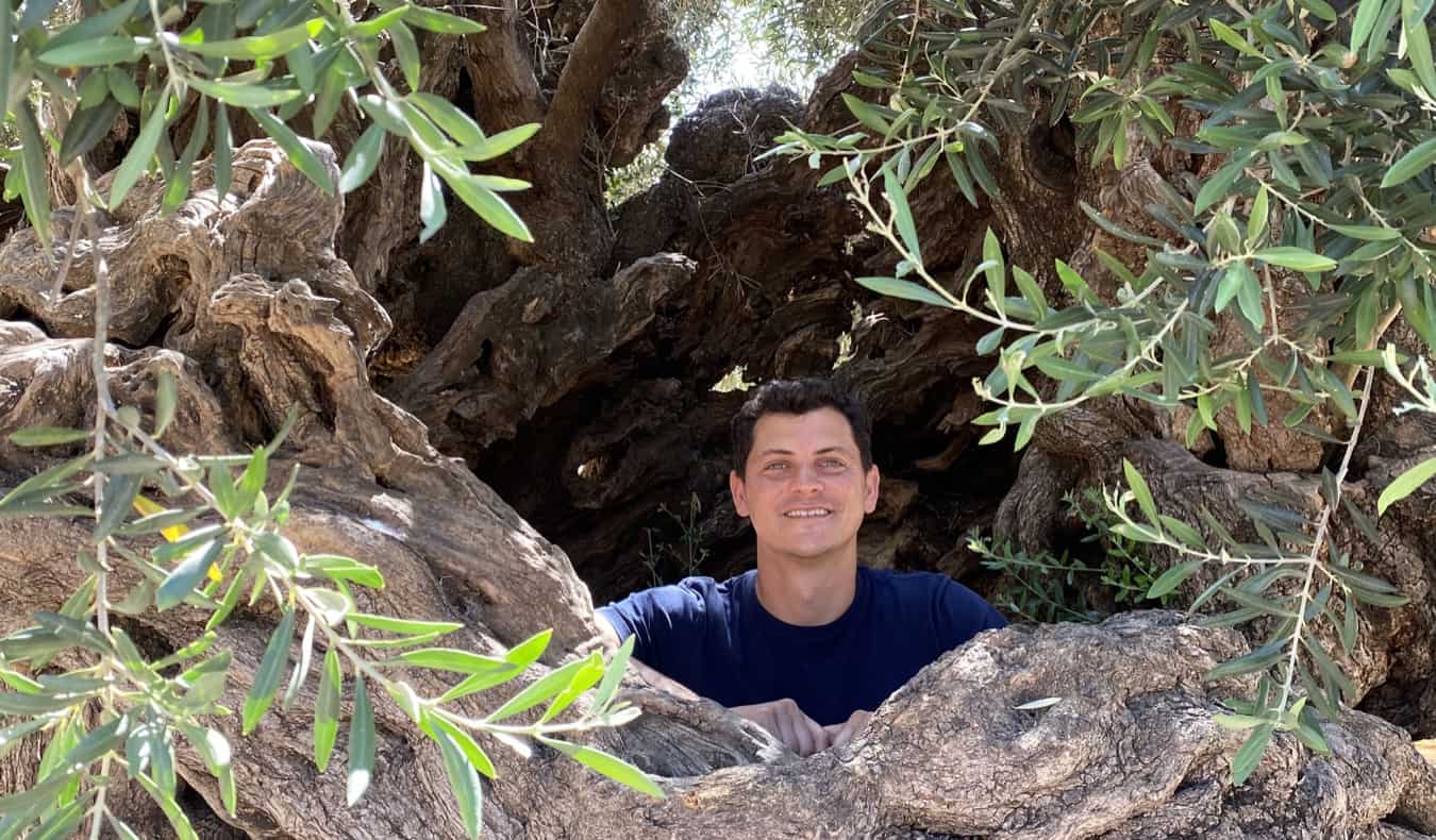 O Nomad Matt olha através do buraco nas rochas na Grécia