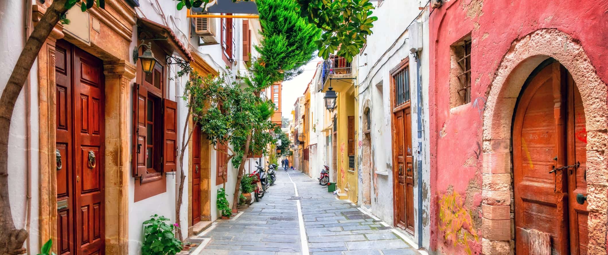 Uma rua pavimentada com casas coloridas com portas de madeira na ilha de Creta, na Grécia.