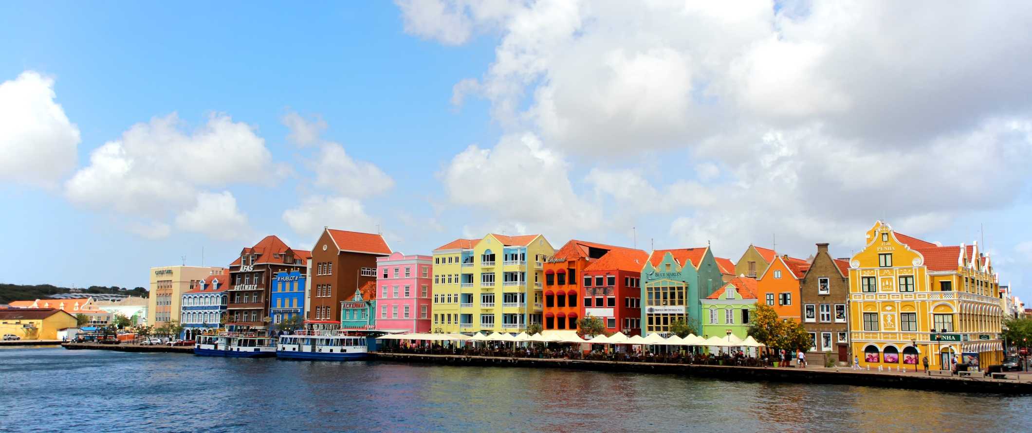Casas pintadas com cores vivas e pessoas jantando no calçadão da ilha tropical de Curaçao, no Caribe
