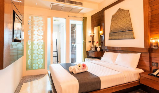 Uma cama de casal em um quarto com paredes de madeira e seu próprio banheiro no albergue D & amp; D Inn