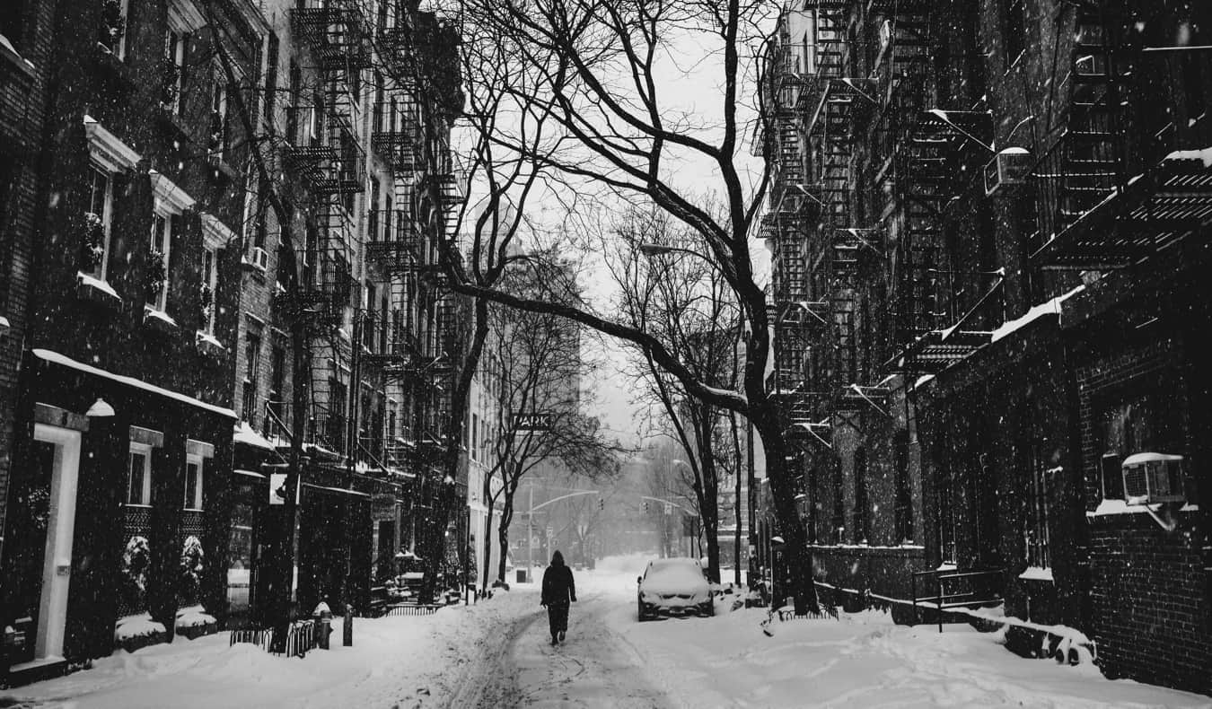 Fotografia em preto e branco de um homem andando na neve em Nova York