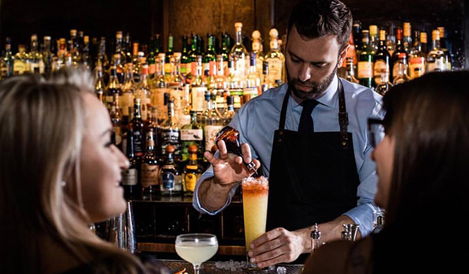 O barman serve coquetéis chiques aos visitantes do Bar Death and Company em Nova York