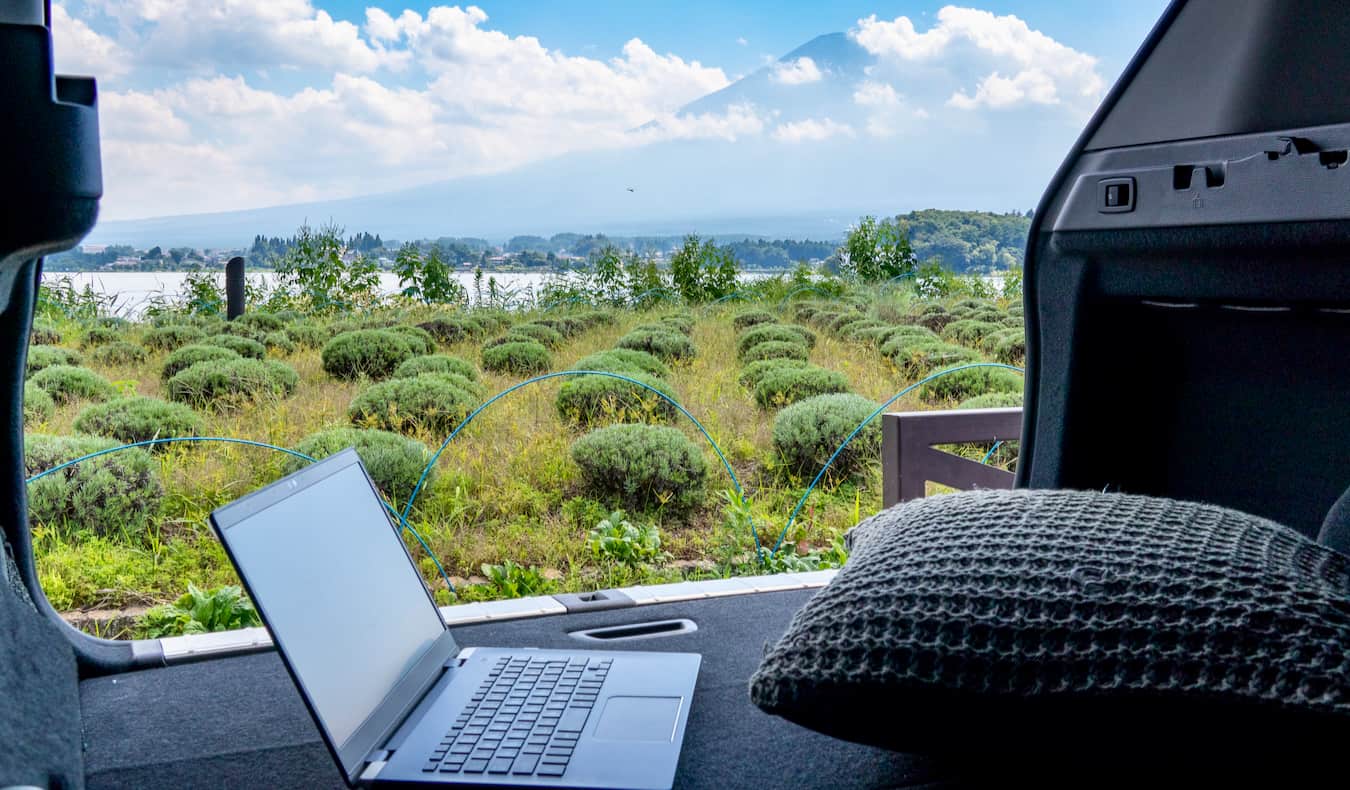 Um laptop em uma van, quando um nômade digital admira o Monte Fuji no Japão