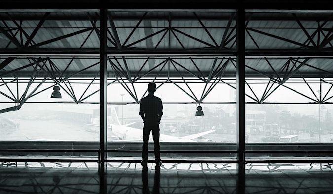 Fotografia em preto e branco de um viajante solitário em pé sozinho no aeroporto