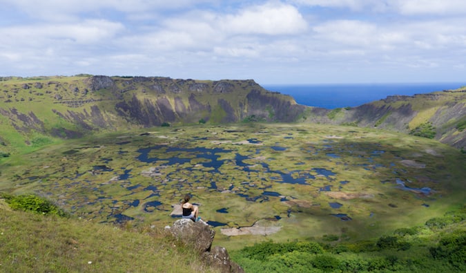 O viajante senta e olha para a paisagem intocada na ilha de Páscoa