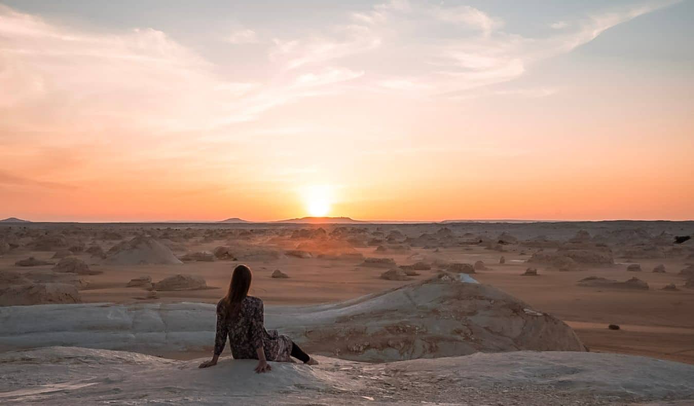 Uma mulher solitária que viaja para a mulher posa no deserto egípcio ao anoitecer