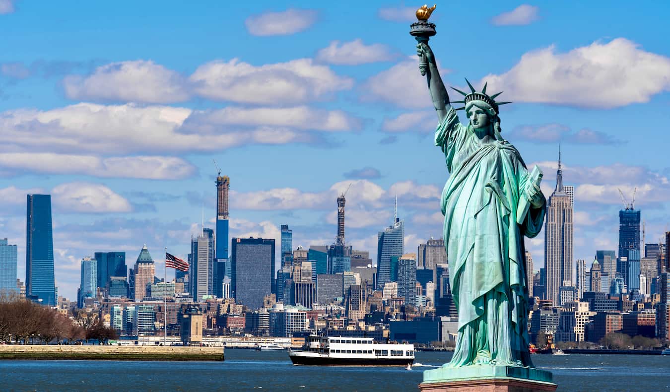 A estátua de Liberdade e Nova York em segundo plano em um dia ensolarado com um céu azul