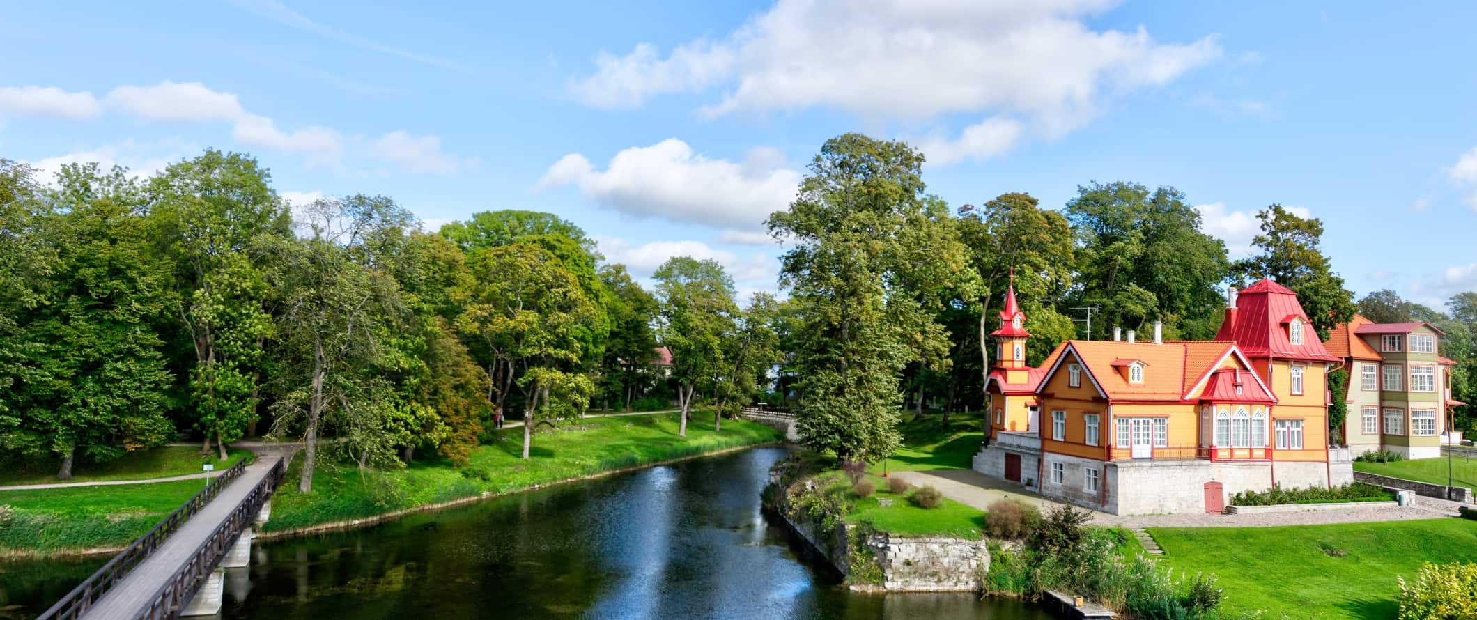Edifícios pintados ao longo do canal, queridos por árvores, na área rural da Estônia