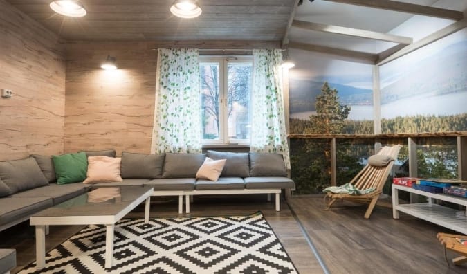 A zona geral do eurohostel do albergue em Helsinque, Finlândia, com sofás cinza, forrado com travesseiros grandes e uma foto de grande escala da paisagem decorando as paredes