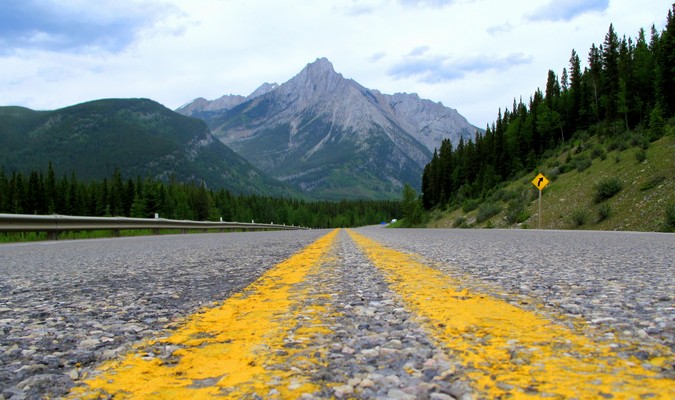 Linhas amarelas de estradas correndo na direção da montanha distante