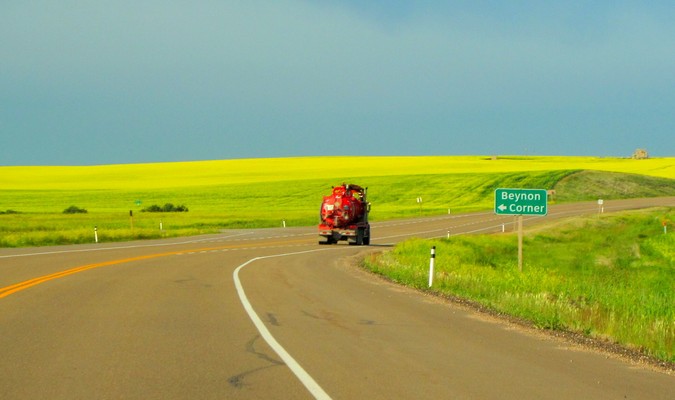 Caminhão vermelho em uma estrada aberta com um campo verde em áreas rurais