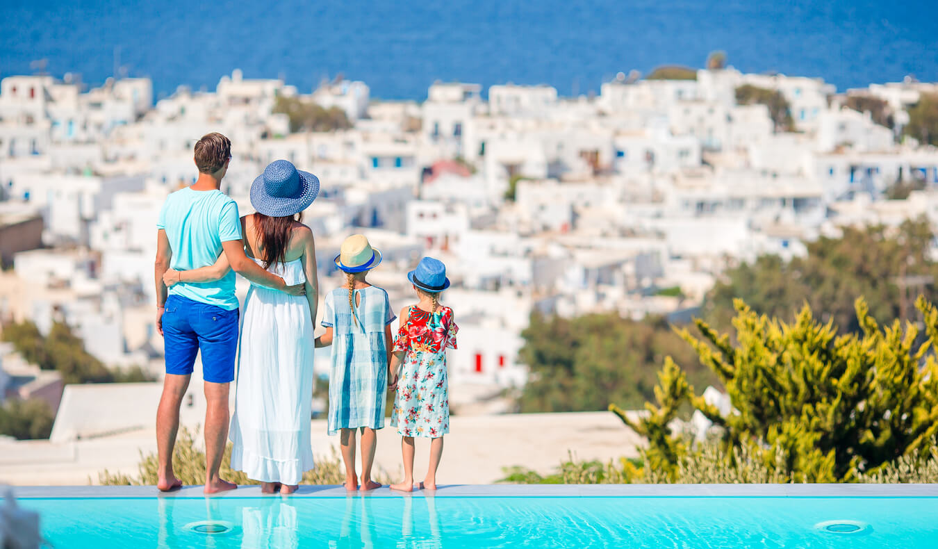 Uma família de viajantes perto de uma piscina à beira da água em uma das ilhas da Grécia