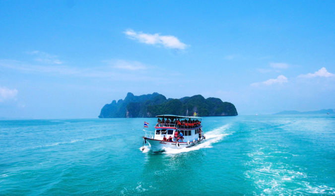 um pequeno barco de transporte na Tailândia partindo de uma pequena ilha.