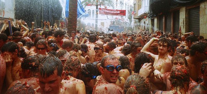 Centenas de pessoas cobertas com tomates no festival de arremesso de tomate La Tomatina na Espanha