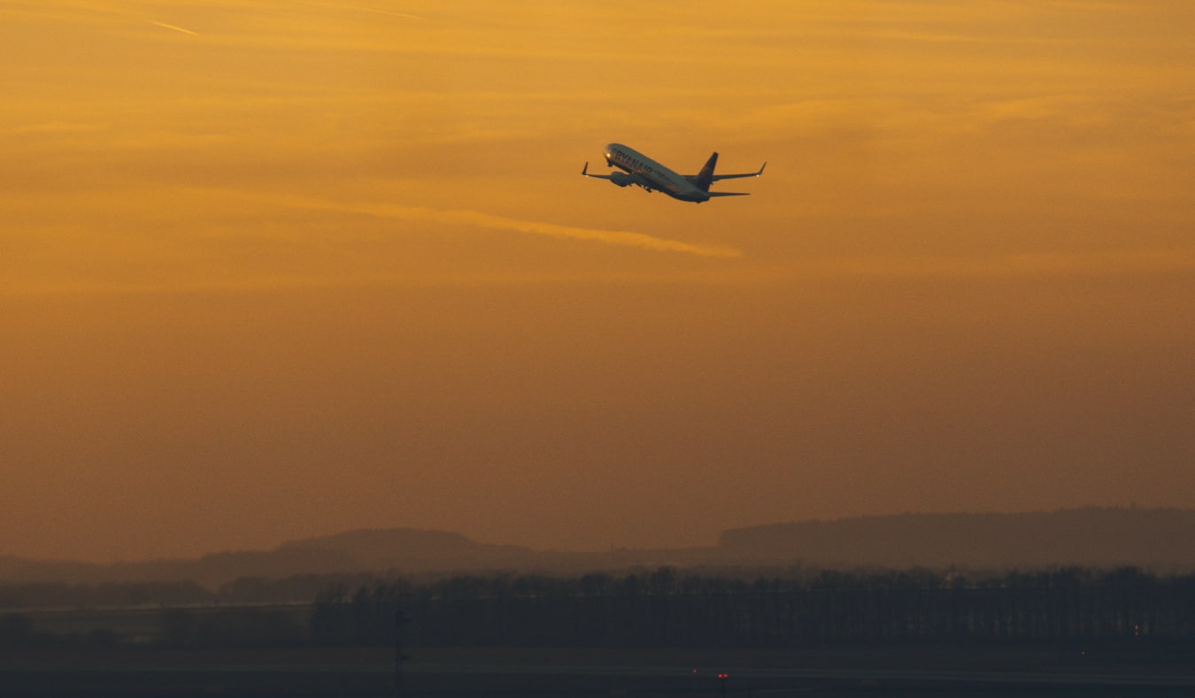 Um avião decolando durante um pôr do sol laranja brilhante.