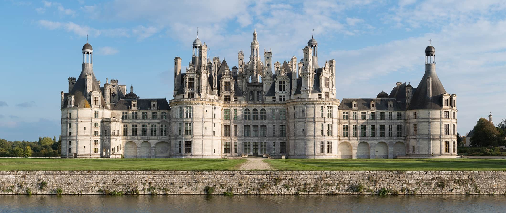 Enorme castelo francês histórico no vale do Loire, cercado por grama e ervas