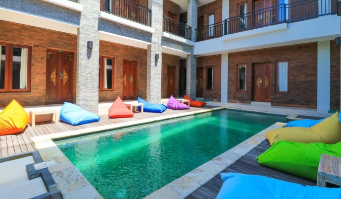 Uma longa piscina de esmeralda, cercada por sacos de feijão com várias colorias no pátio do Gelatik Bed & amp Hotel; Café da manhã em Seminayak, Bali