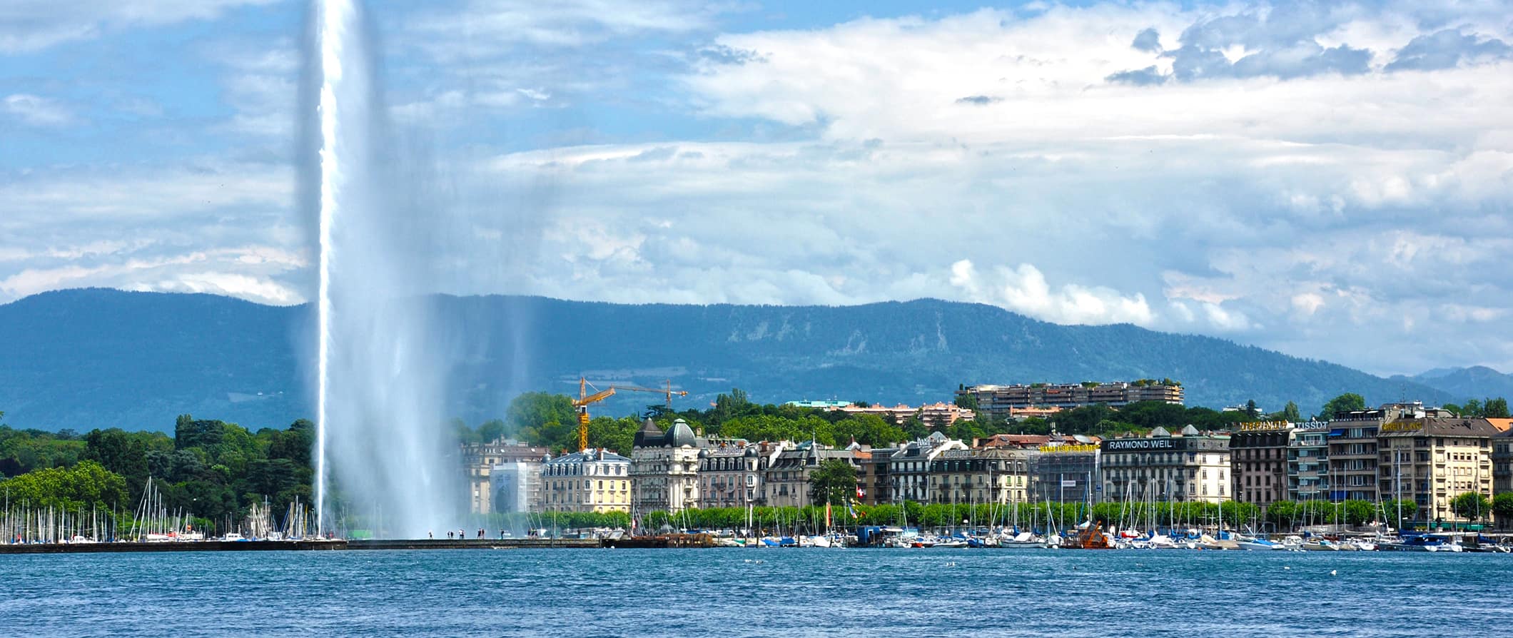 Vista da fonte e do aterro em Genebra, na Suíça, em um dia de verão brilhante e ensolarado com montanhas à distância