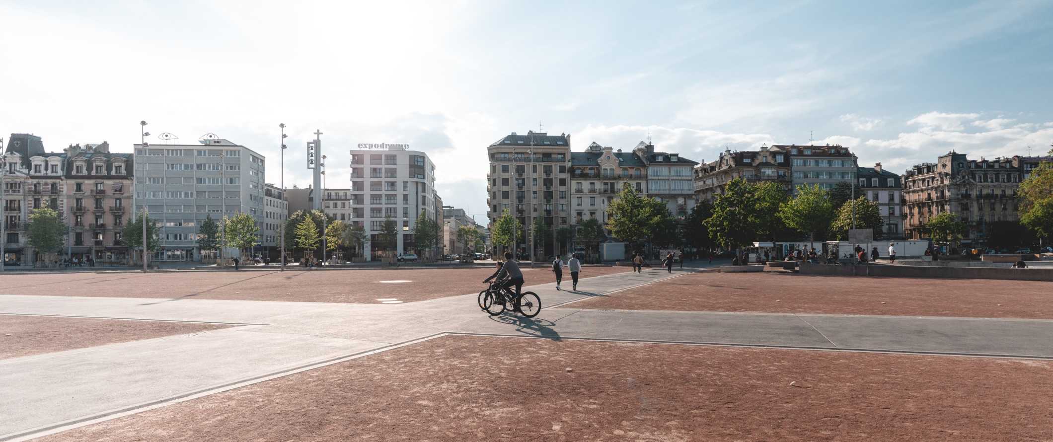 As pessoas andam a pé e andam de bicicleta em uma grande praça em Genebra, na Suíça