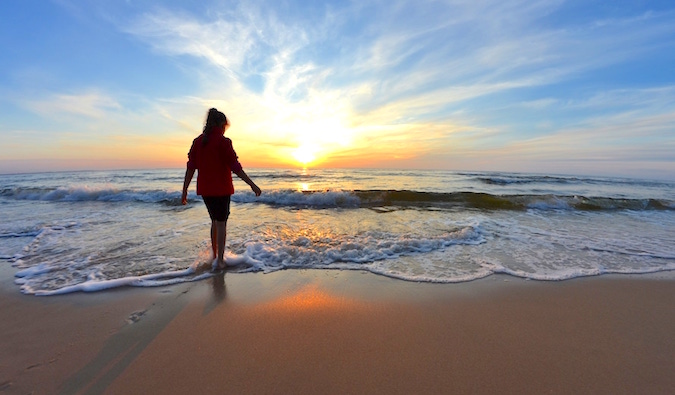 Mulher solitária anda descalça em uma praia pitoresca