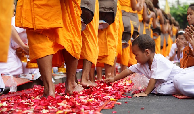A criança toca as pétalas de rosas que estão nos monges
