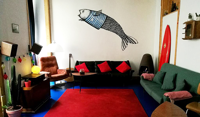 Área comum com espreguiçadeiras e um grande peixe pintado na parede do Goodnight Hostel, Lisboa
