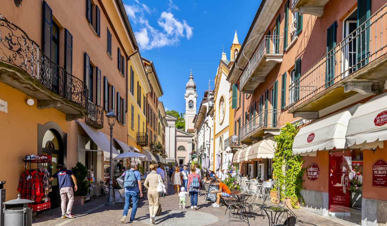 As pessoas exploram uma rua estreita em uma cidade colorida na bela Itália ensolarada