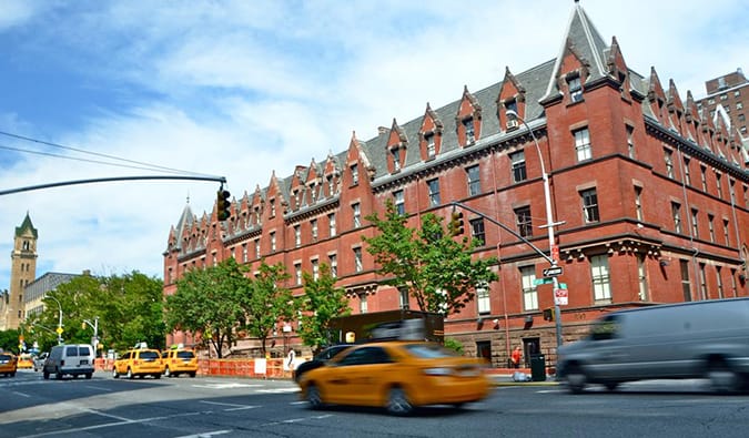 Um grande edifício de tijolos com passagem de táxi amarelo por Hi New York em Nova York