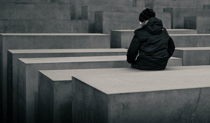 Uma pessoa está sentada em um dos pilares de concreto do memorial dos judeus assassinados da Europa em Berlim, Alemanha