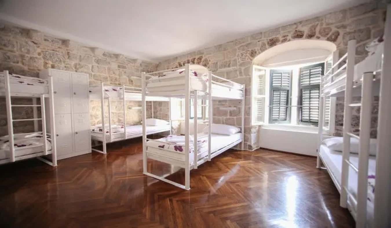 O número total com beliches, um piso de madeira e paredes de pedra no albergue de Angelina em Dubrovnik, Croácia.