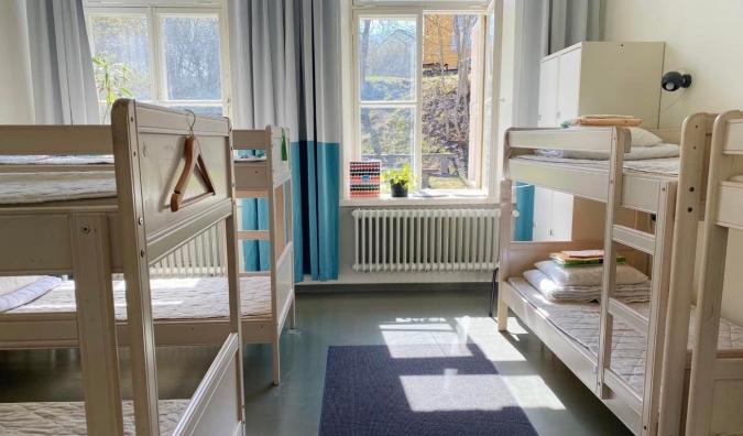 A sala comum no Hostel Suomenlinna em Helsinque, Finlândia, com beliches de madeira branca e luz solar natural.