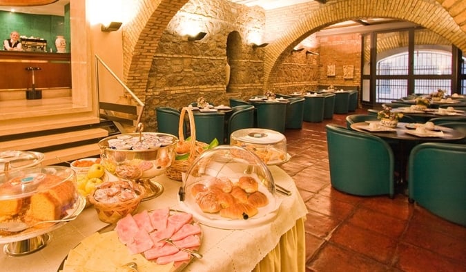 Buffet de café da manhã na área de jantar com tetos em arco de pedra do Laurentia Hotel em Roma, Itália