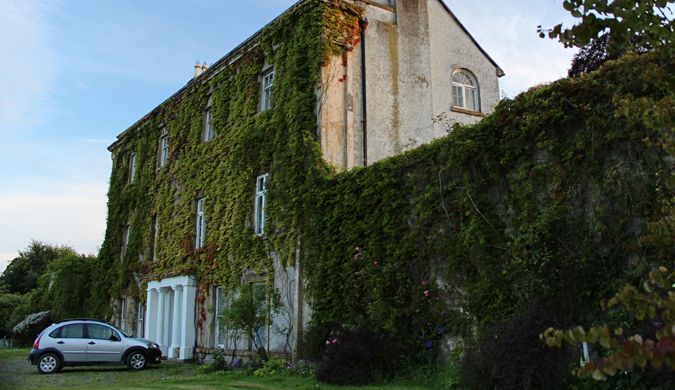Bela mansão coberta com vinhedos com um carro em frente à casa na Escócia