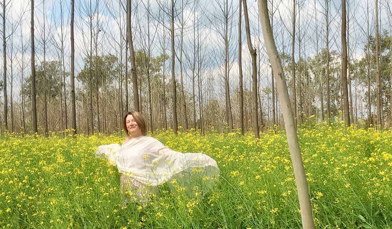 Uma mulher solteira na Índia posa em um campo verde cercado por grama e árvores