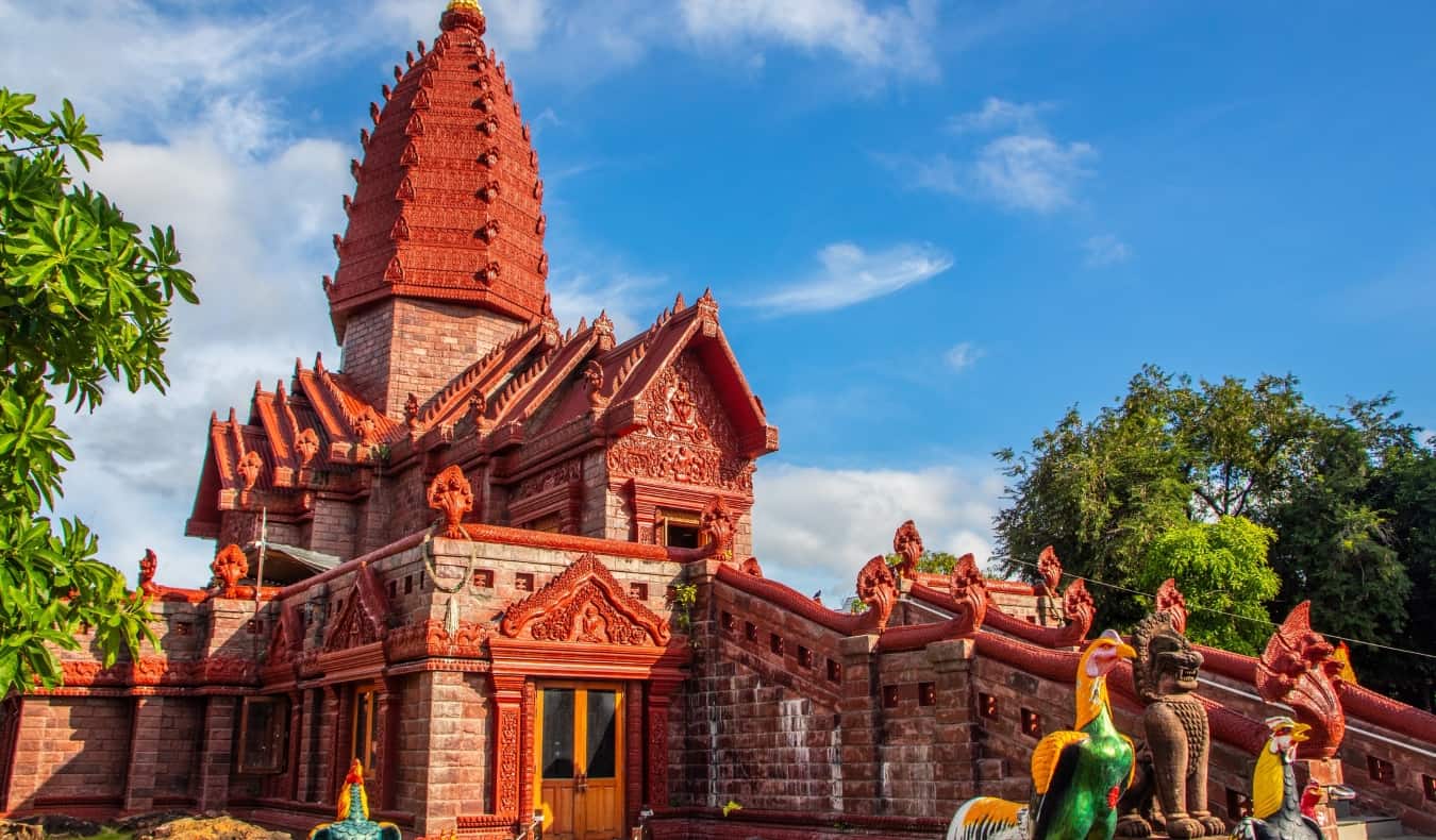 Templo vermelho brilhante e ricamente decorado Wat Phrai Phatthana em Isaan, Tailândia