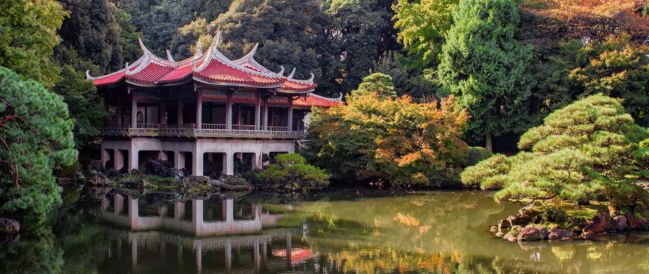 Templo antigo no Japão cercado por árvores exuberantes por um pequeno lago