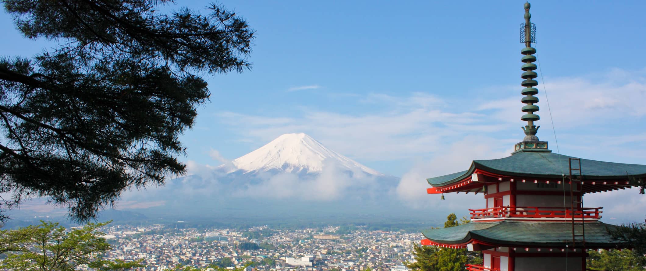 Monte Fuji à distância em um dia ensolarado com um pagode em primeiro plano no Japão