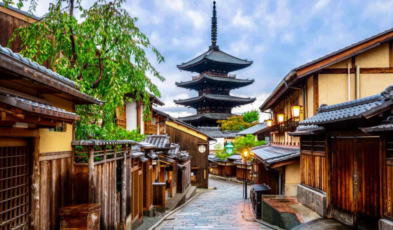 Uma rua antiga estreita em quieto Kyoto, Japão, com um pagode à distância