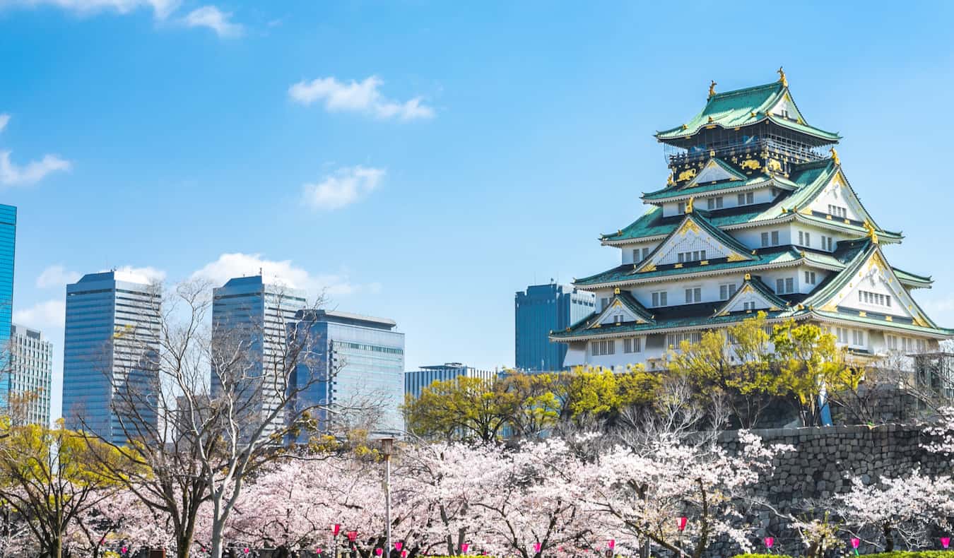 O famoso castelo de Osaka, elevand o-se sobre um animado Osaka, Japão, em um dia ensolarado