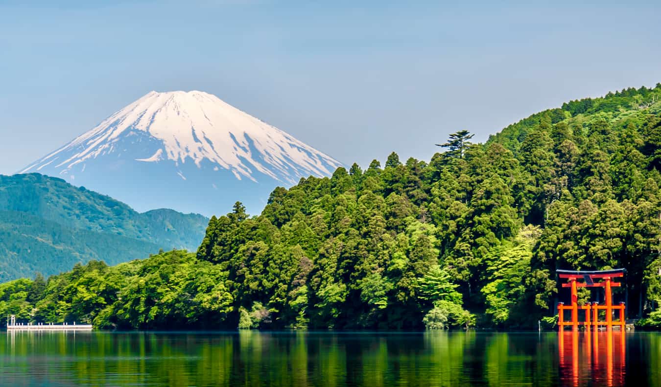 Portão vermelho de Toria em água com ervas exuberantes e Monte Fuji no fundo Japão