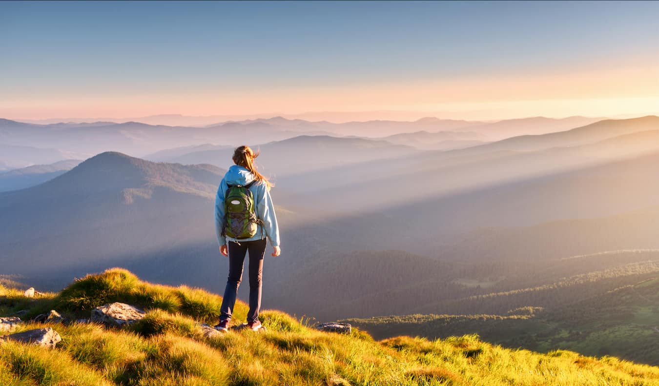 Viajante solitário de mulher enquanto caminhava nas colinas ao pôr do sol