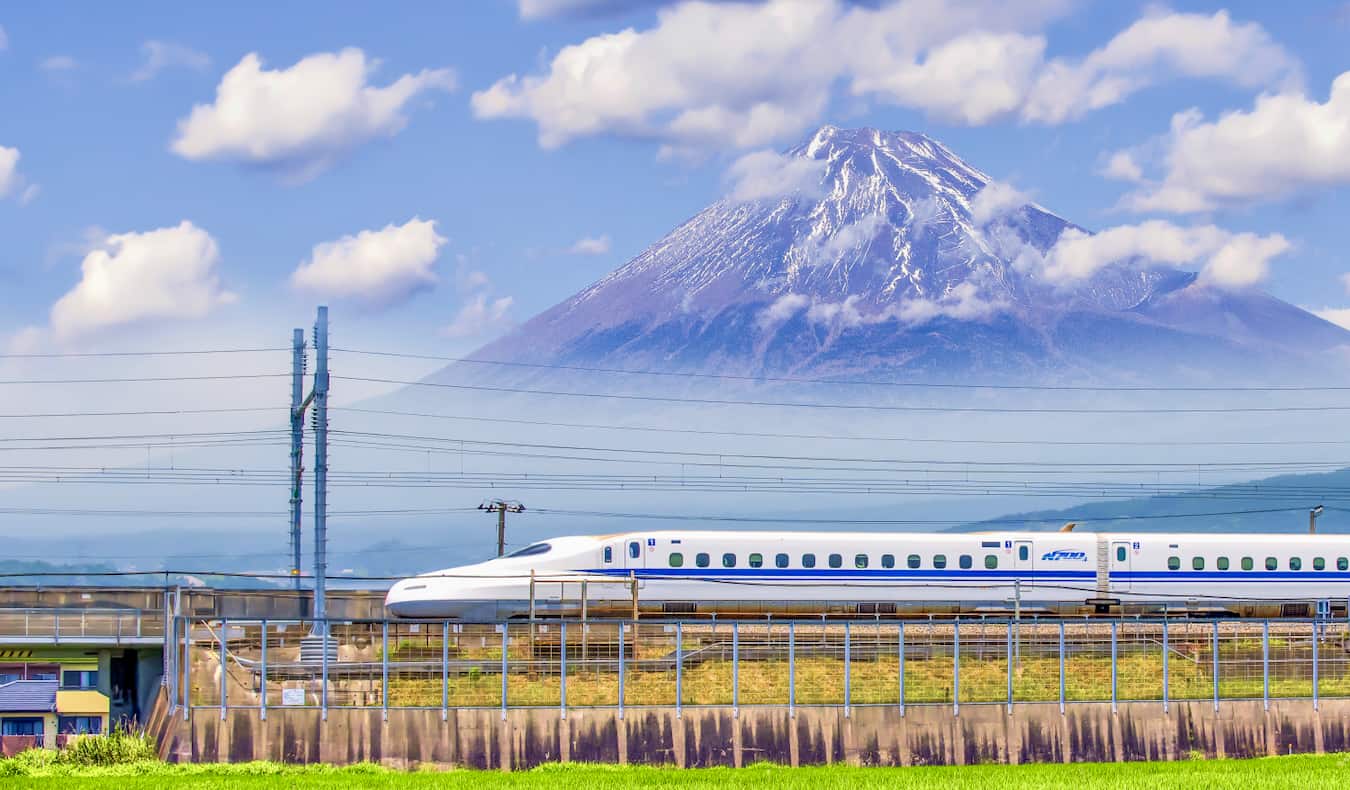 Os trens de caules drivam em frente ao famoso Monte Fuji em segundo plano no Japão