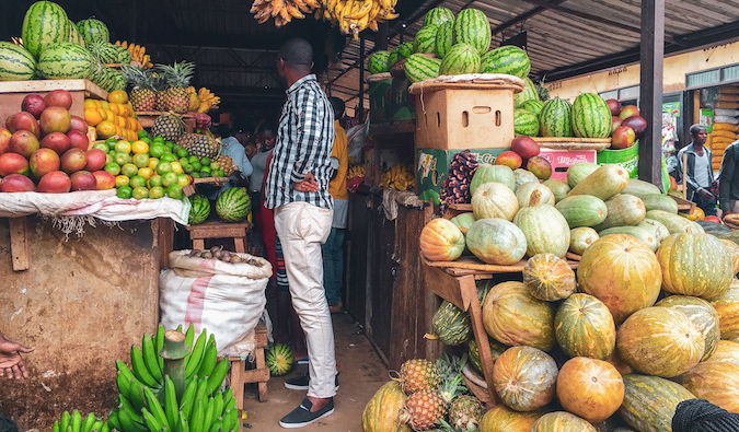 Um homem em Ruanda fica em um supermercado cercado por frutas frescas